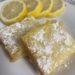 Lemon Bars on white plate with lemon slices in background
