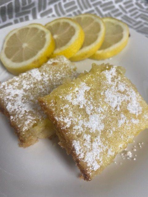 Lemon Bars on white plate with lemon slices in background