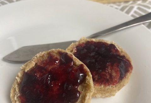 Round scones with jam on white plate.