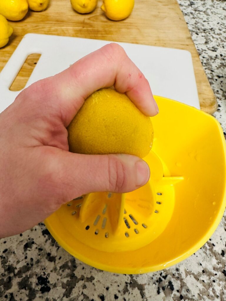 Hand squeezing lemon with citrus juicer