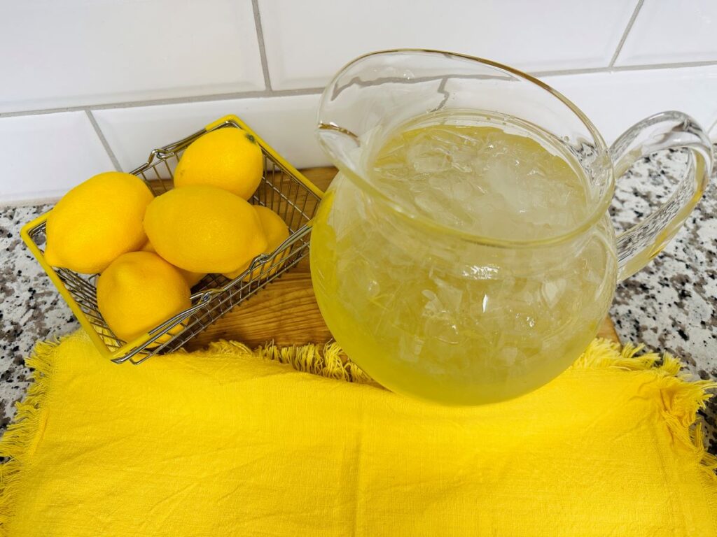 Pitcher of lemonade next to basket of lemons