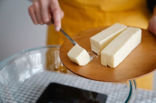 Person adding block of butter to glass dish.