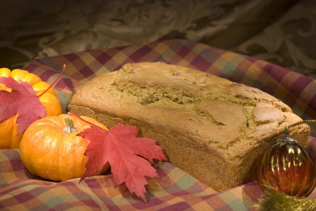 Pumpkin bread next to pumpkins and leaves.