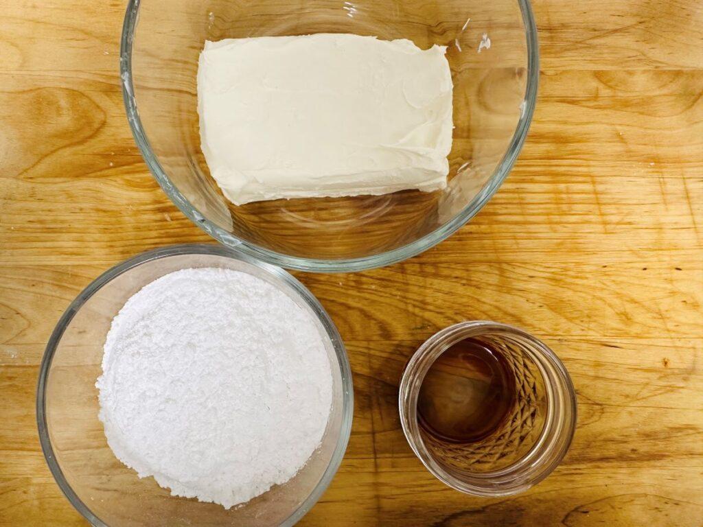 Ingredients for cream cheese frosting on wooden board.