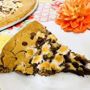 Slice of chocolate chip dessert pizza on white plate.
