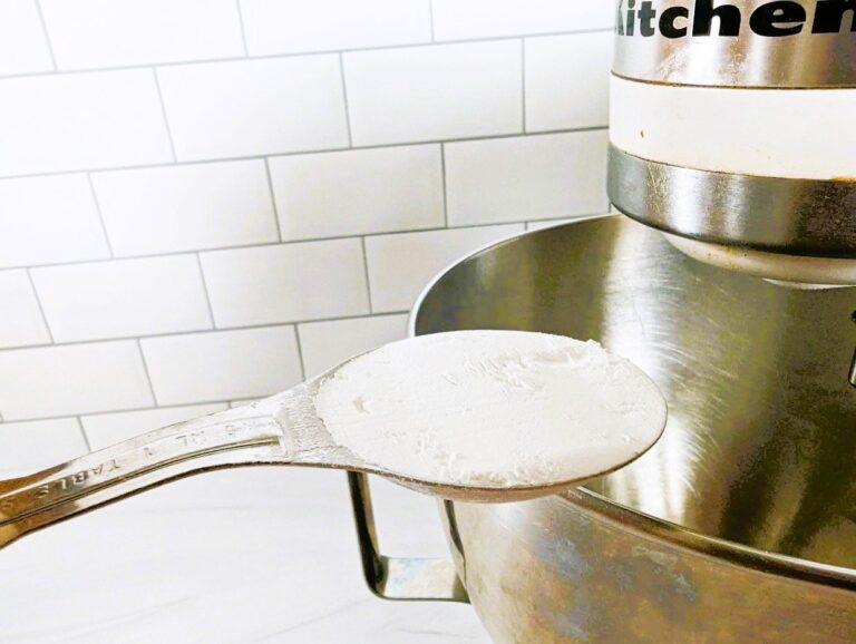 Spoon of baking powder over mixing bowl.