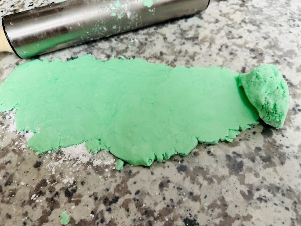 Green dough rolled flat on waxed paper.