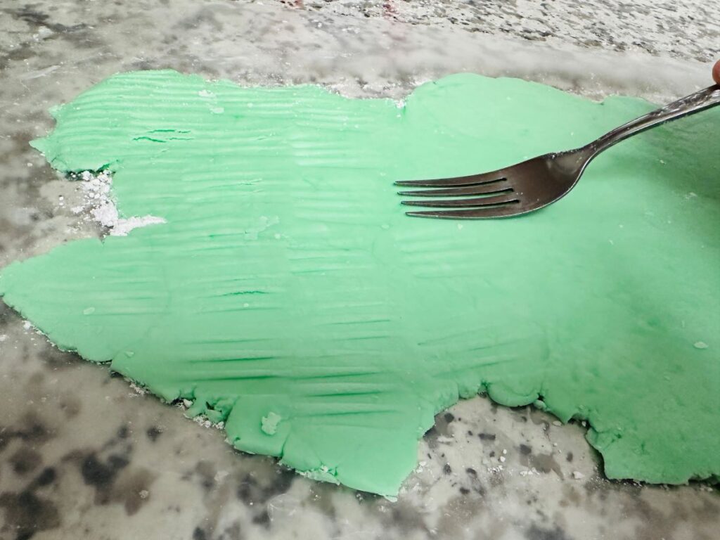 Flat green dough with silver fork on top.