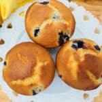 Overhead view of 3 blueberry muffins on white plate.