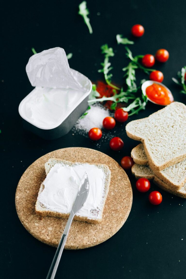 Cream cheese on toast with cherry tomatoes in the background.