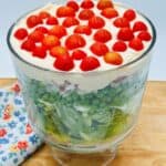 Green lettuce and green peas in clear bowl with mayonnaise and cherry tomatoes on top.
