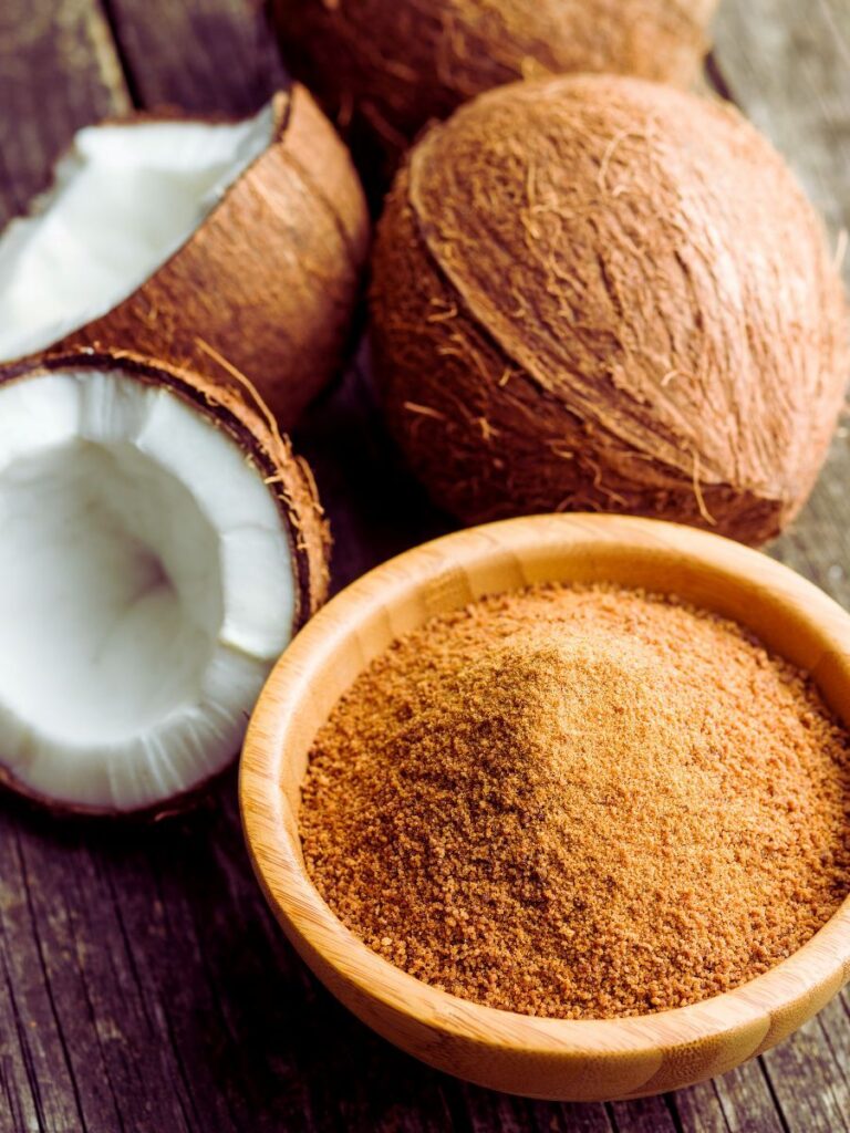 Brown powder in wooden dish in front of coconuts.