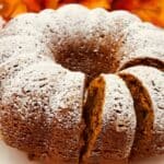Dark orange bundt cake topped with powdered sugar with slices cut and leaning against each other.