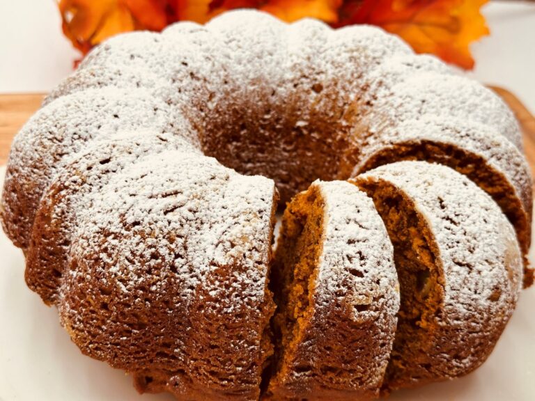 Dark orange bundt cake topped with powdered sugar with slices cut and leaning against each other.