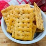 Golden seasoned rectangular crackers in white bowl.