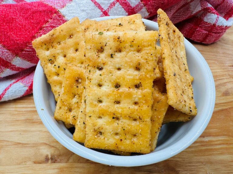 Golden seasoned rectangular crackers in white bowl.
