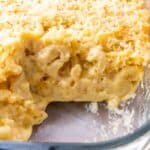 Macaroni and cheese in glass dish with one serving missing.