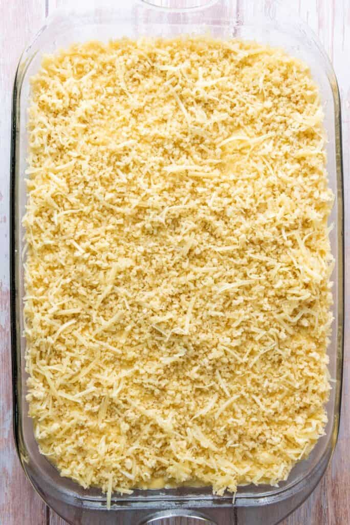 Macaroni and cheese with crumb topping in rectangular glass casserole dish before baking.