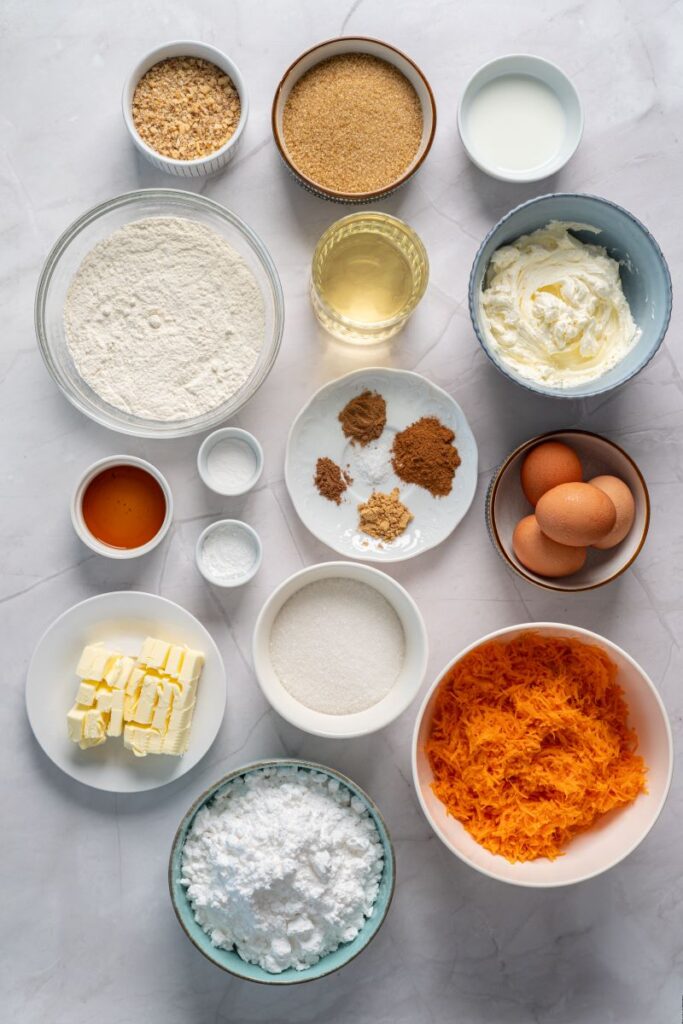 Top view of ingredients for carrot cake in white dishes on marble background.