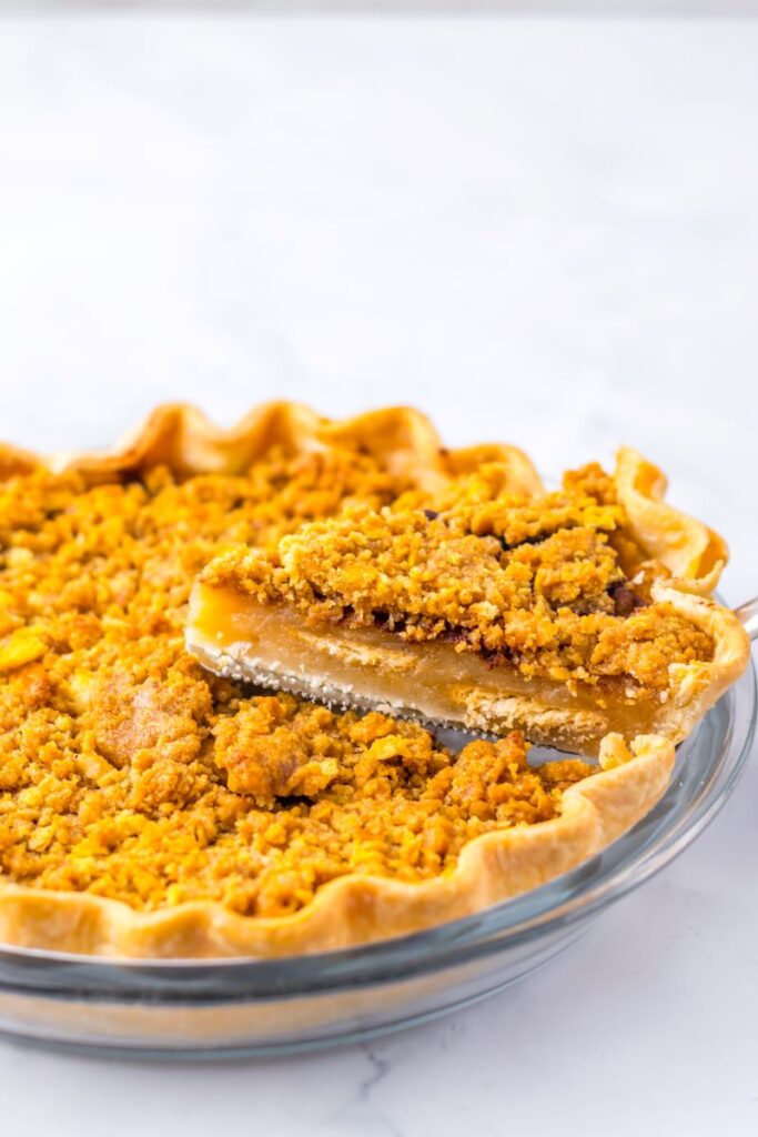 Slice of pie being lifted out of pie dish with silver pie server.