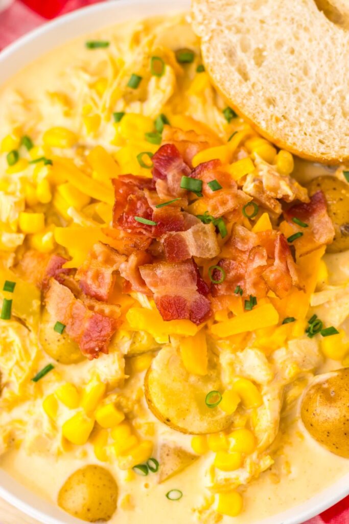 Close up of overhead shot of chicken corn chowder in white bowl with French bread on the side.