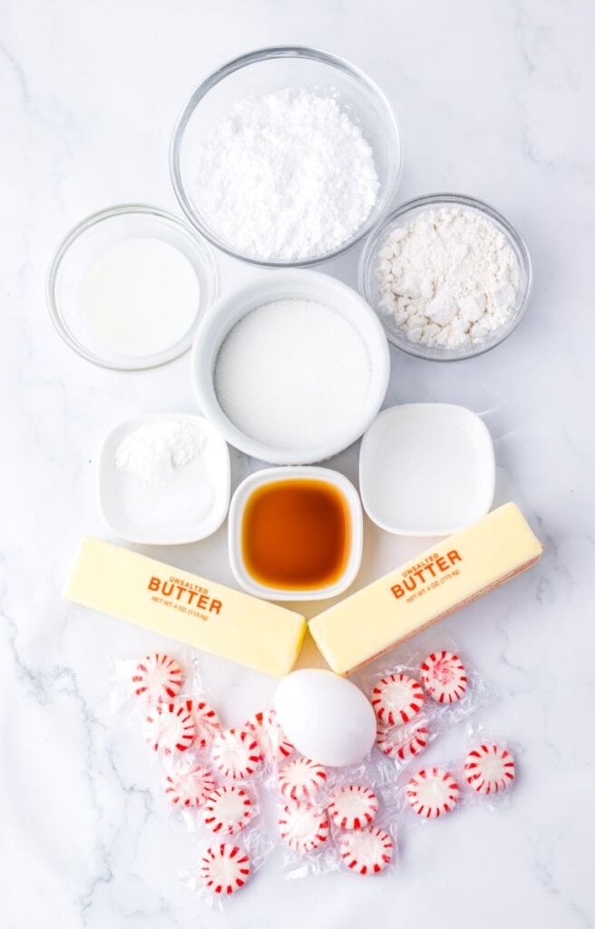 Ingredients for Peppermint Sugar Cookie Bars in white bowls on marble surface.