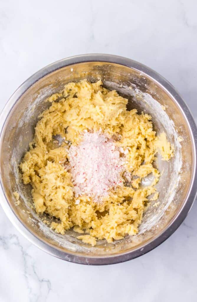 Light tan dough with crushed peppermints on top in silver bowl.