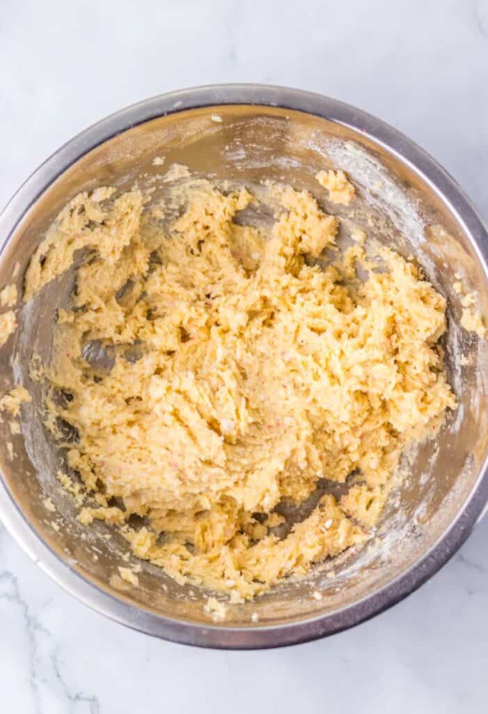 Tan cookie dough in silver bowl.