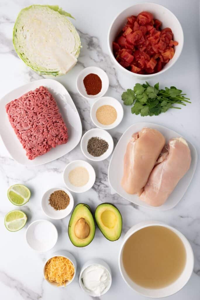 Ingredients for taco soup in white bowls on marble counter.