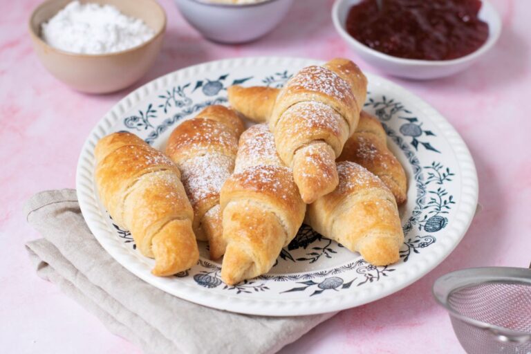 Close up of plate of croissants with powdered sugar on top.