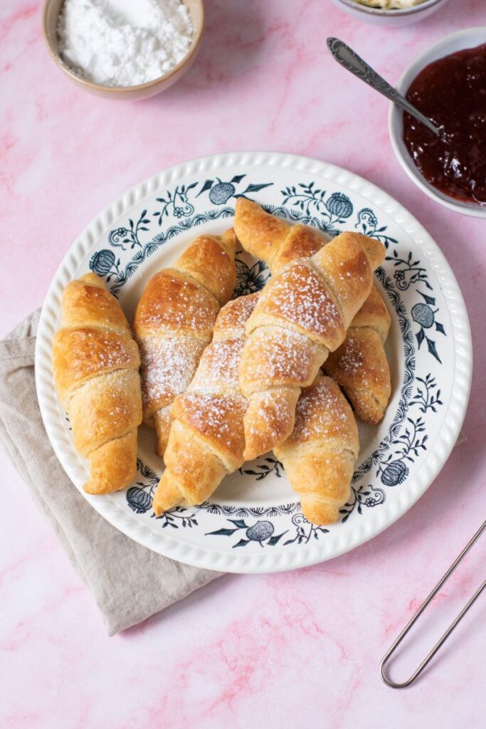 Top view of plate of croissants with powdered sugar.