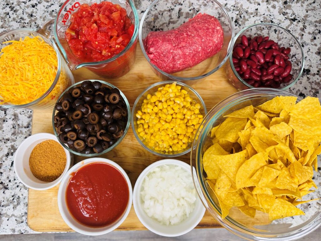 Ingredients for Mexican casserole in bowls on wooden board.