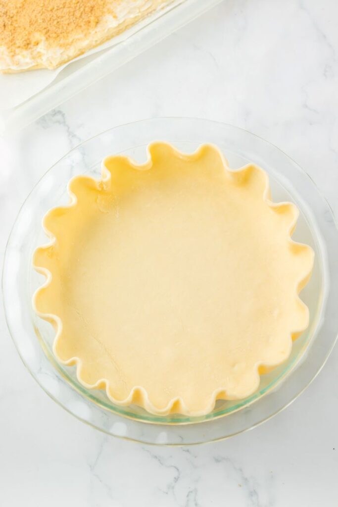 Top view of unbaked pie crust in glass pie dish.