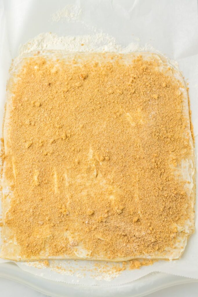Rolled out dough in rectangular shape with cinnamon sprinkled on top.