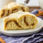 Side view of slice of cinnamon roll pie on white plate.