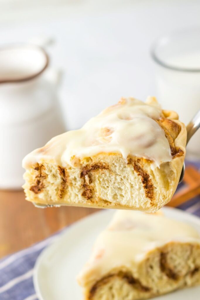 Side view of slice of cinnamon roll pie on silver pie server.