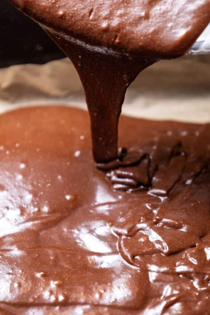 Brown batter being poured into baking pan.