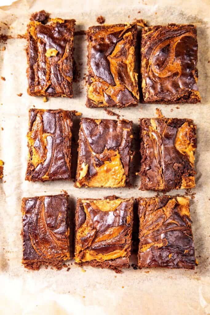 Nine chocolate peanut butter brownies on parchment paper.