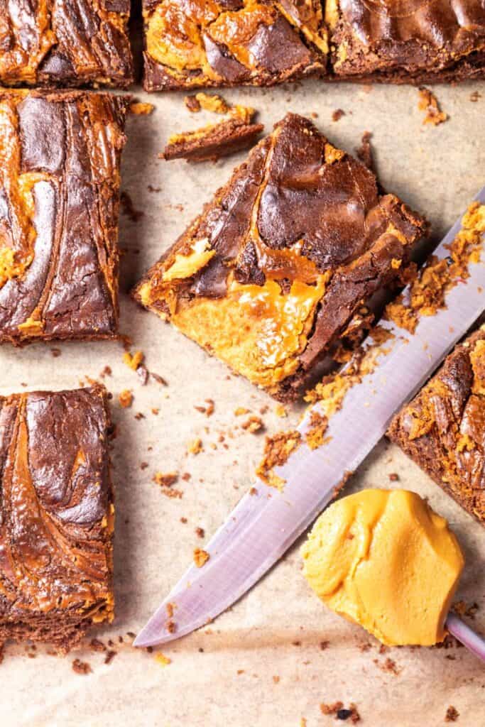 Chocolate peanut butter brownies next to knife and spoon of peanut butter.