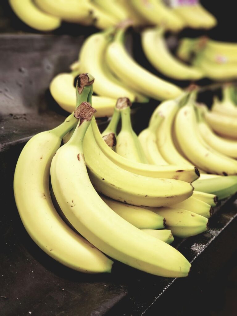 Bunches of bananas on black shelves.