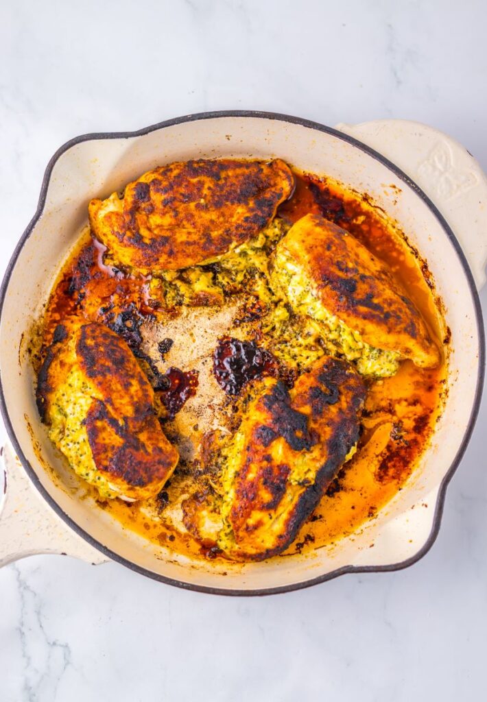 Top view of stuffed chicken cooking in pot on white background.