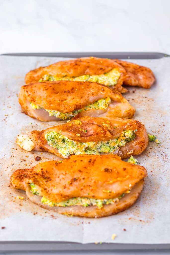 Side view pf raw chicken stuffed with broccoli and cheese.