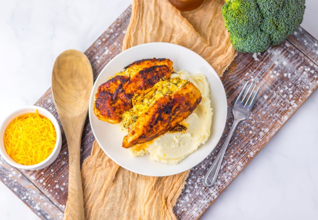 Top view of cooked stuffed chicken on white plate with mashed potatoes.