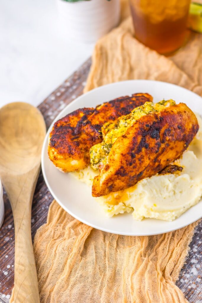 Cooked chicken on white plate with mashed potatoes.