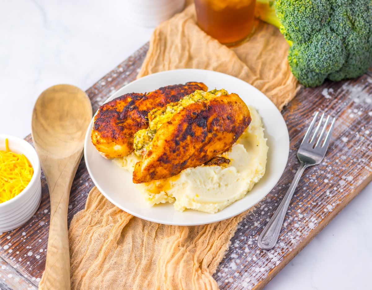 Cooked stuffed chicken on white plate with mashed potatoes.