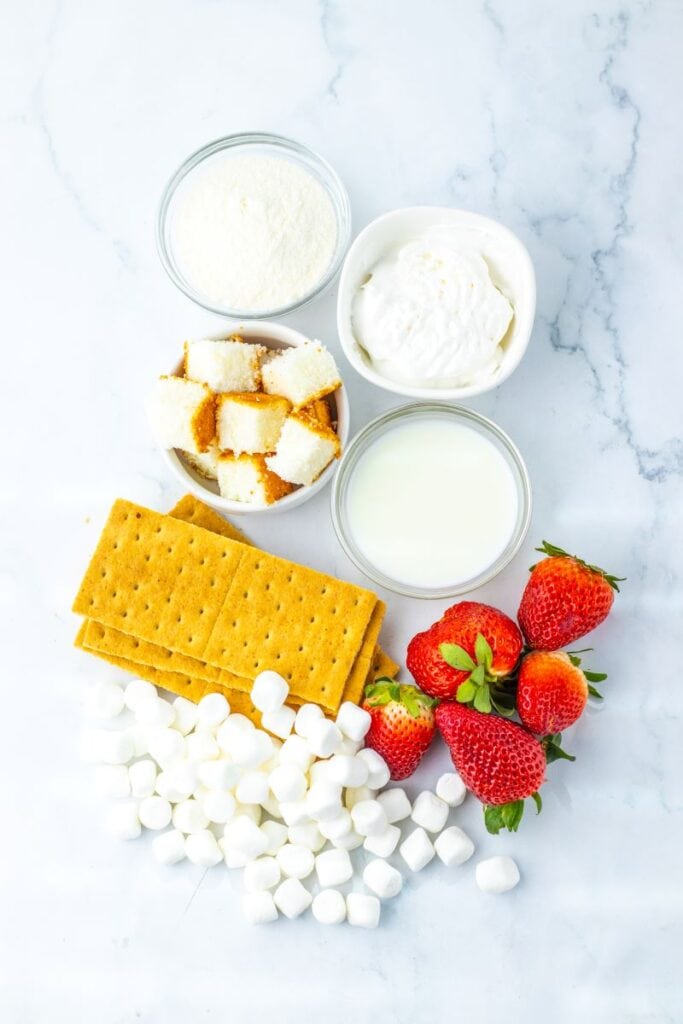 Top view of ingredients for strawberry shortcake fluff on marble background.