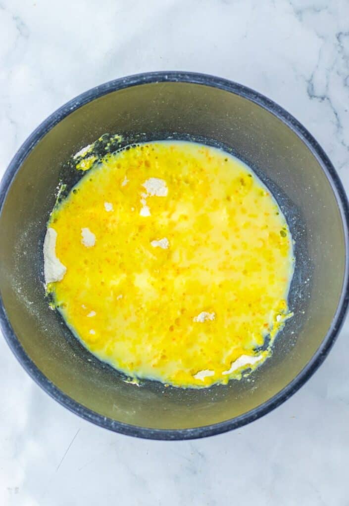Milk and yellow pudding mix in dark blue bowl.