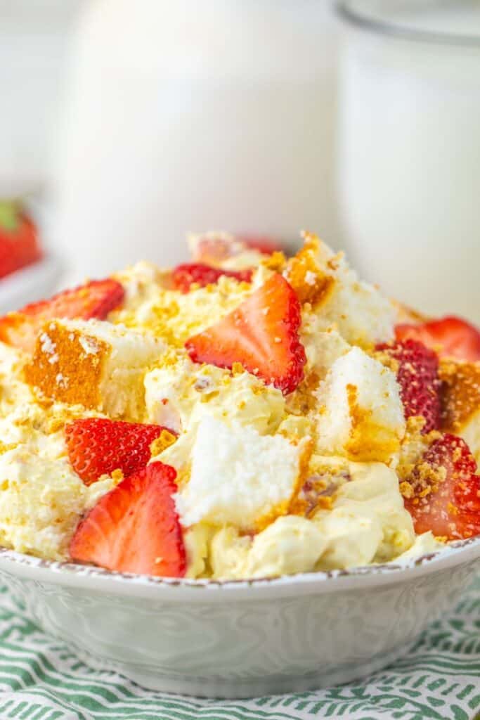 Closeup view of strawberry shortcake fluff salad on green and white towel with milk in the background.