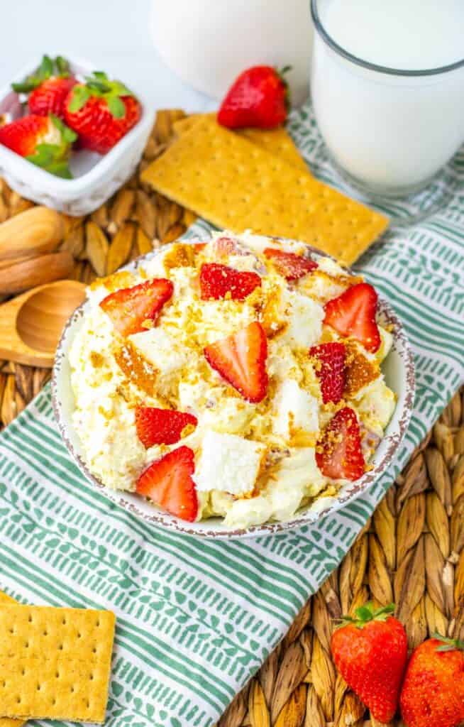 Top view of strawberry shortcake fluff salad on green and white towel with milk and strawberries in the background.