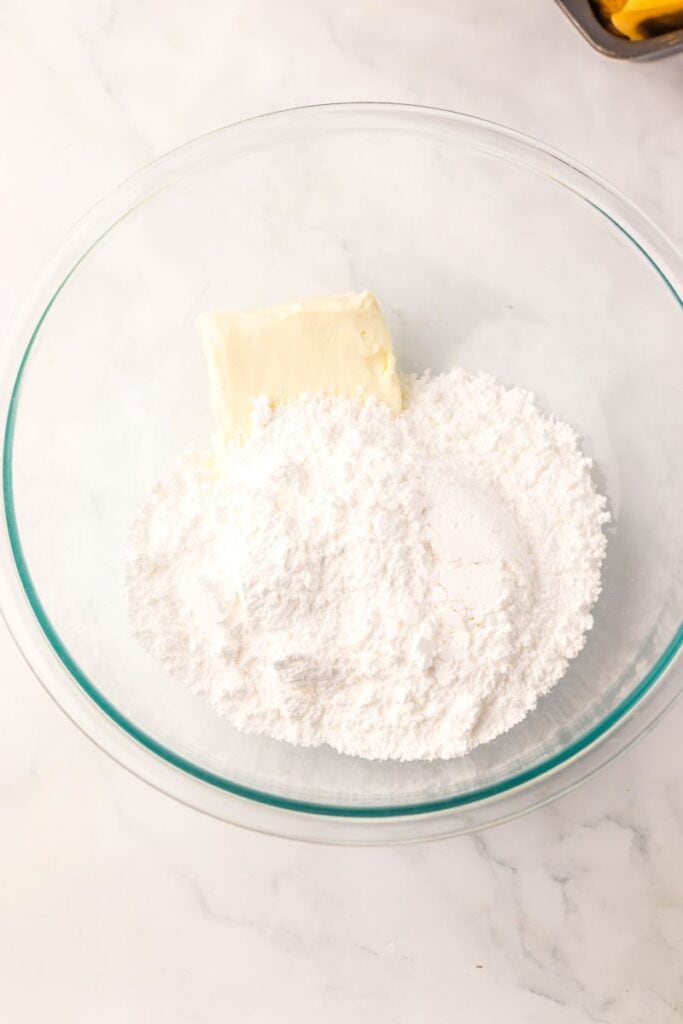 Ingredients for cream cheese frosting in glass bowl.
